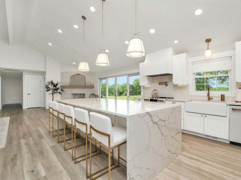 Example of a remodeled kitchen with a large island and white cabinets