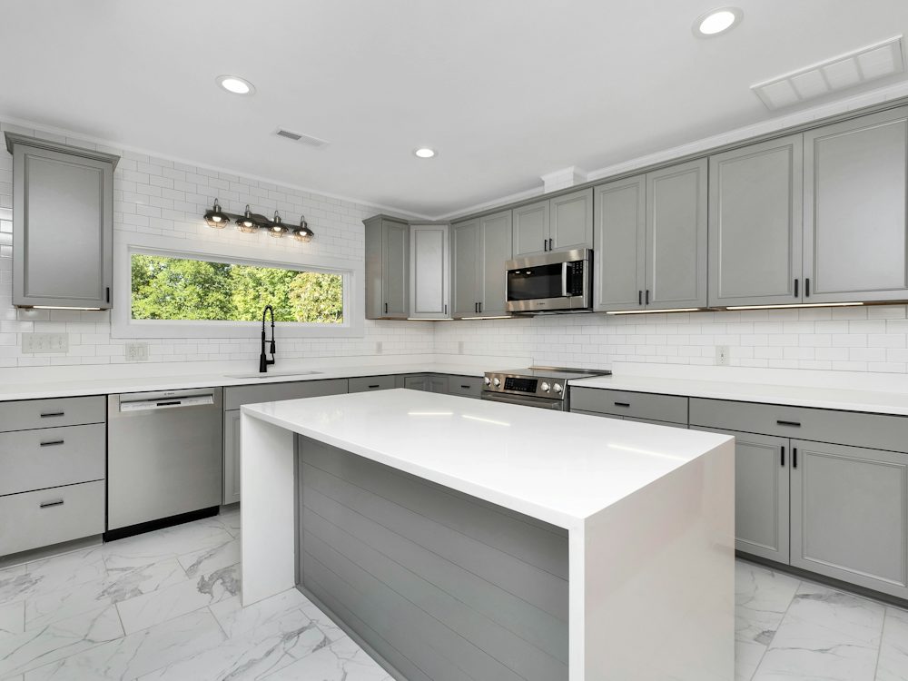 Example of a remodeled kitchen with gray cabinets and an island